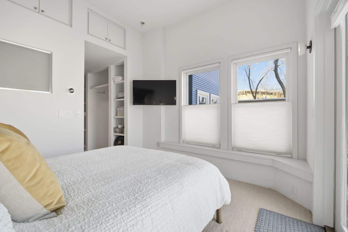 Een slaapkamer met een bed, een televisie en een raam met zonwering.