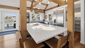 Una cocina moderna con una isla grande, vigas de madera y electrodomésticos de acero inoxidable.