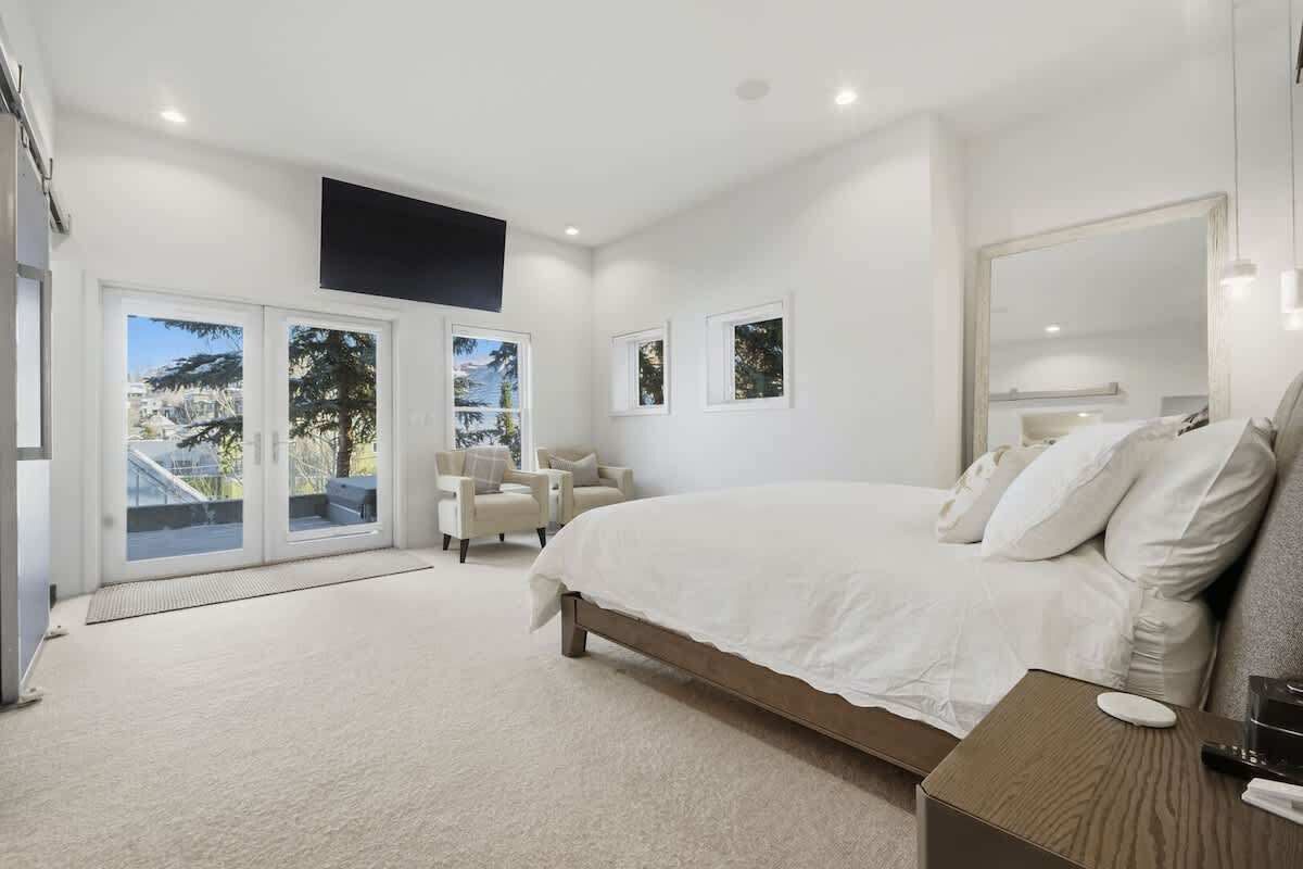 Ein Schlafzimmer mit einem großen Bett, einer Sitzecke mit Sesseln und Blick durch eine Glastür.