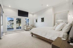 A bedroom with a large bed, a seating area with chairs, and a view through a glass door. - Old Town Park City House Walk to Main Street (Park City)