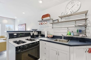 A modern kitchen with a gas stove, oven, white cabinets, a sink, and a clock on the wall. - Old Town Park City House Walk to Main Street (Park City)