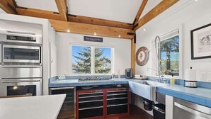Una cocina moderna con electrodomésticos integrados, un ventanal grande y techo de madera.