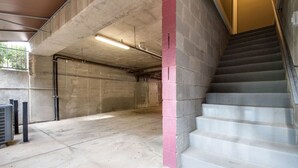 Un escalier en béton menant à un niveau inférieur, avec une rambarde en métal et un luminaire fluorescent.