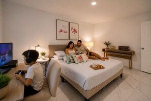 Een slaapkamer met een bed, nachtkastje, lamp en een televisie.