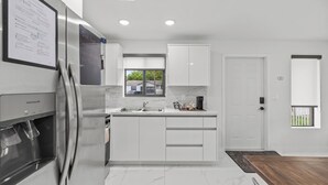 A modern kitchen with a built-in refrigerator, a sink, and a window. - Urban Sabor - Modern Miami - King Beds - Fenced Yard - Parking (Miami)