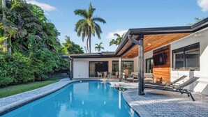 A modern house with a swimming pool, outdoor furniture, and lush greenery. - Coral Lane by Rove Travel Heated Pool & BBQ (Fort Lauderdale)