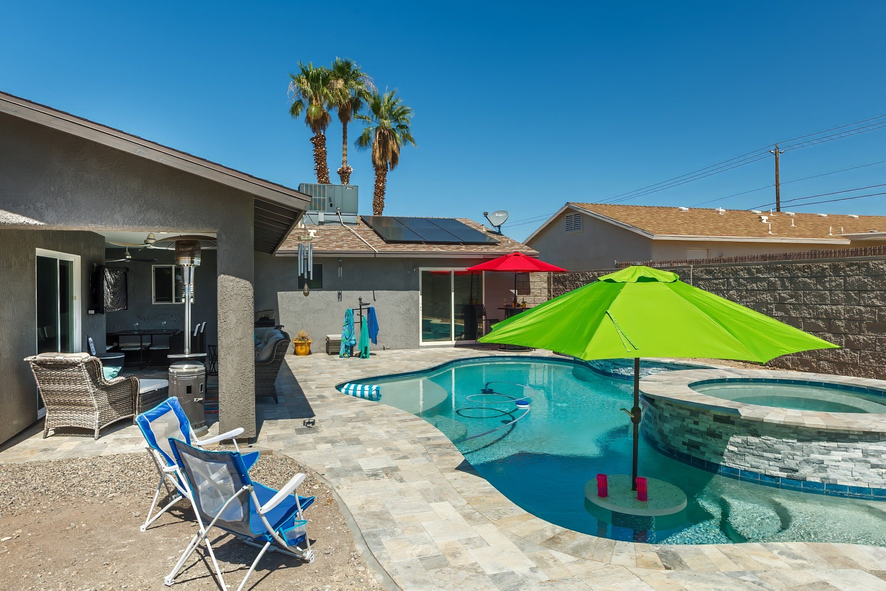 A backyard with a swimming pool, patio furniture, and a red umbrella.
