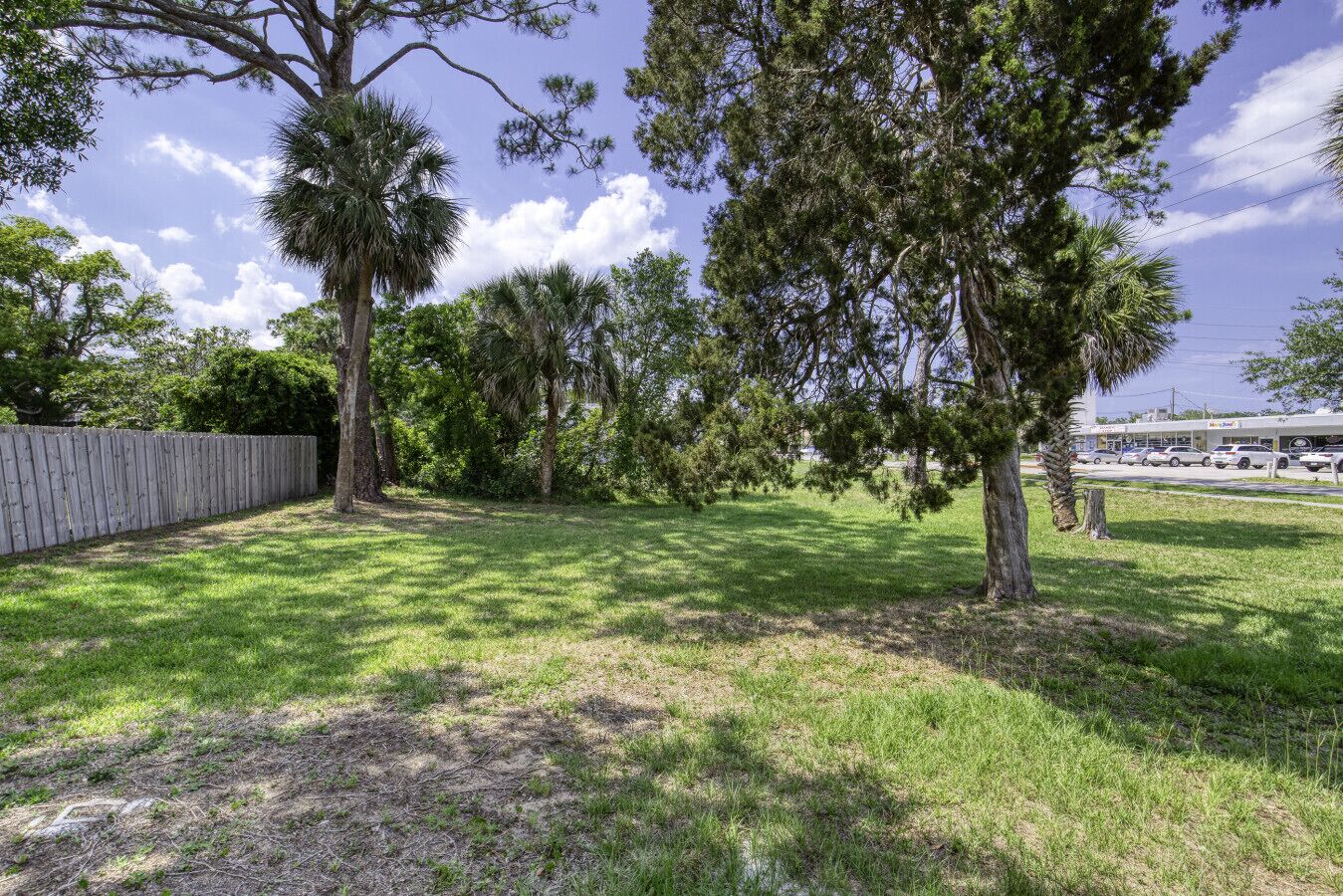 A grassy area with trees and a wooden fence.