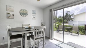 Ein Essbereich mit Tisch und Stühlen, einem Deckenventilator und Blick ins Freie durch große Schiebeglasüren.