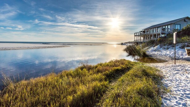 A beachfront property with a wooden structure, a sandy beach, and a calm body of water. - Coastside (Santa Rosa Beach)