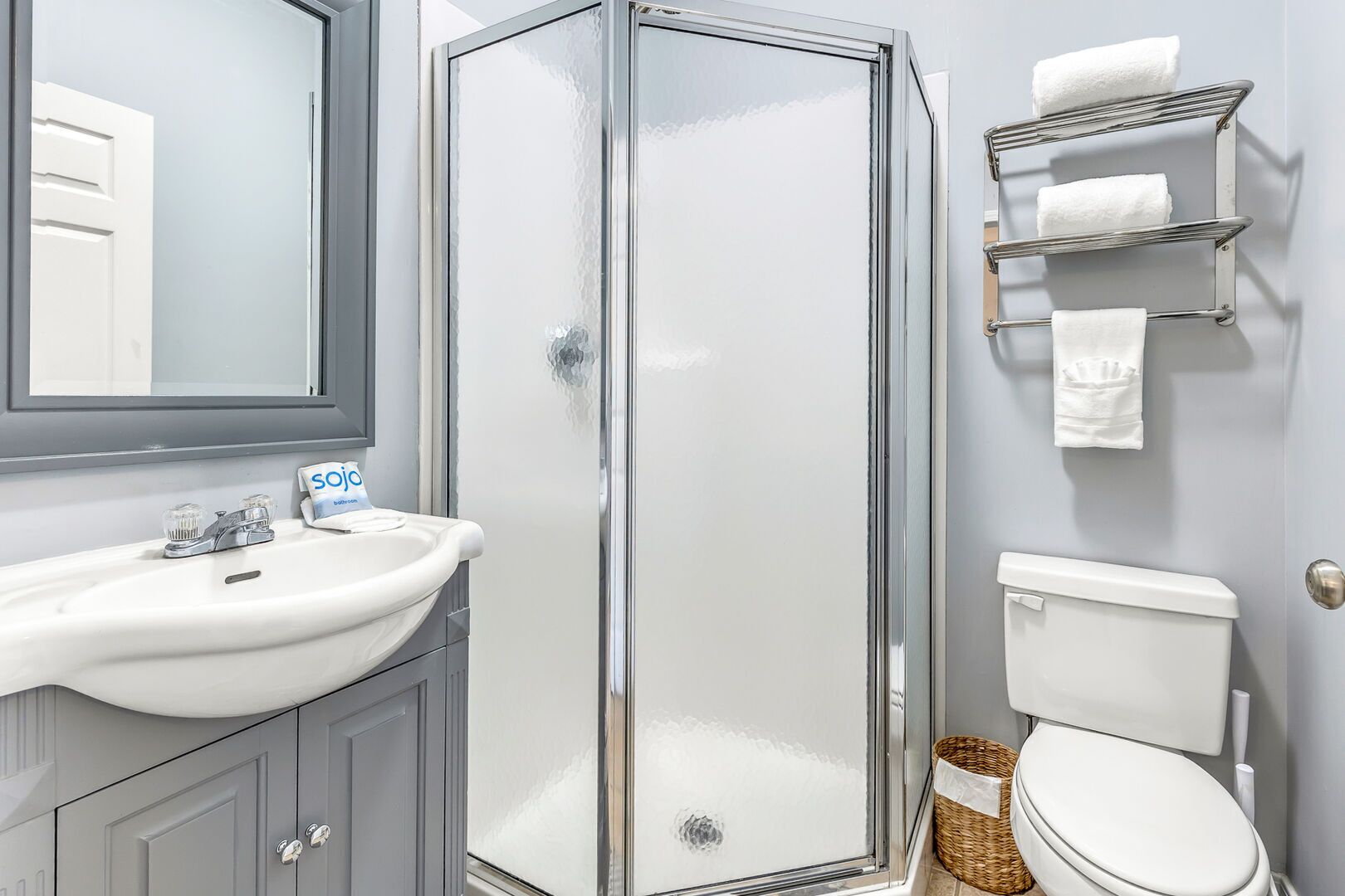 A bathroom with a glass-enclosed shower, a white sink, a toilet, and a towel rack.