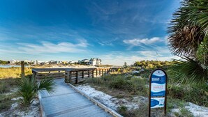 A wooden boardwalk leading to a beach area with a signboard. - Coastside (Santa Rosa Beach)