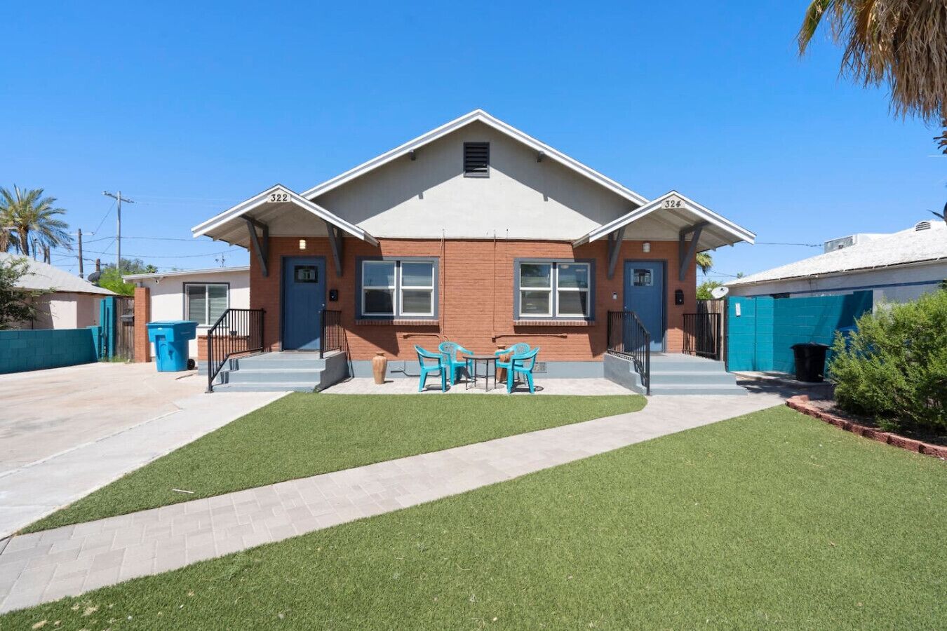 A two-story building with a flat roof, a front porch, and a small lawn with outdoor furniture.