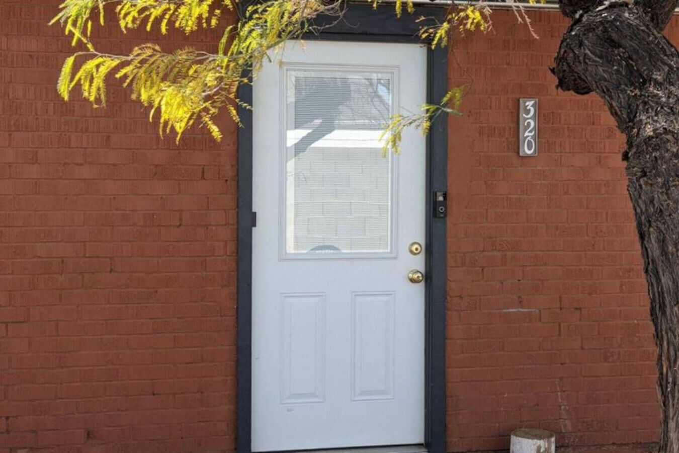 A white door with a window above it, set in a brick wall.
