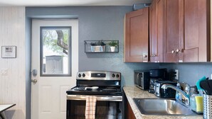 A kitchen with a stove, microwave, sink, and wooden cabinets. - Cute & Cozy Renovated APT in the Heart of Phoenix (Phoenix)