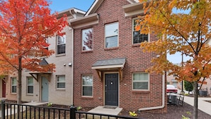 A two-story brick building with a black front door, windows, and a small porch. - Cozy and Comfortable 1-br in the Heart of Detroit (Detroit)