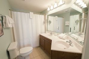 A bathroom with a toilet, sink, and mirror. - Coconut Grove - 403 (North Myrtle Beach)
