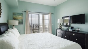 A bedroom with a large bed, a dresser, a TV, and a balcony with a view. - Coconut Grove - 403 (North Myrtle Beach)