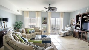 A spacious living room with a sectional sofa, a coffee table, and a television. - Coconut Grove - 403 (North Myrtle Beach)