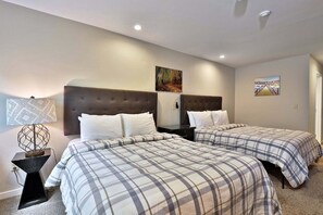 Habitación de hotel con dos camas, una mesita de noche, una lámpara y dos cuadros colgados en la pared.