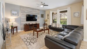 A living room with a leather sofa, a TV, a wooden entertainment unit, and a decorative rug. - Cup8949 (Kissimmee)