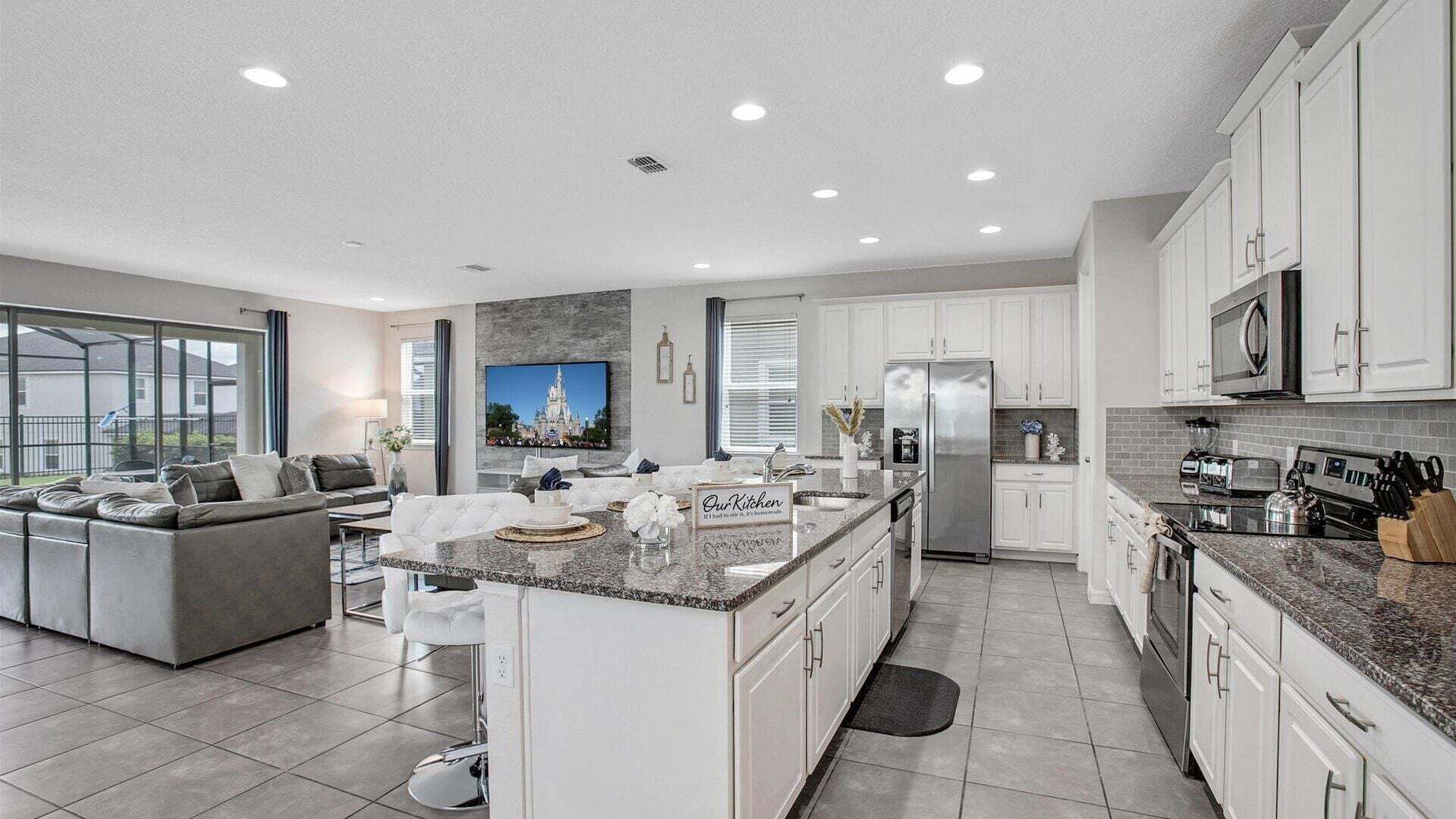 A modern kitchen with white cabinets, a stainless steel refrigerator, and a large island.