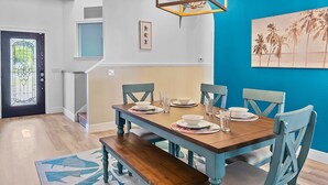 A dining area with a wooden table set for four, surrounded by chairs, a bench, and a chandelier. - Coastal Oasis 3 (Nokomis)