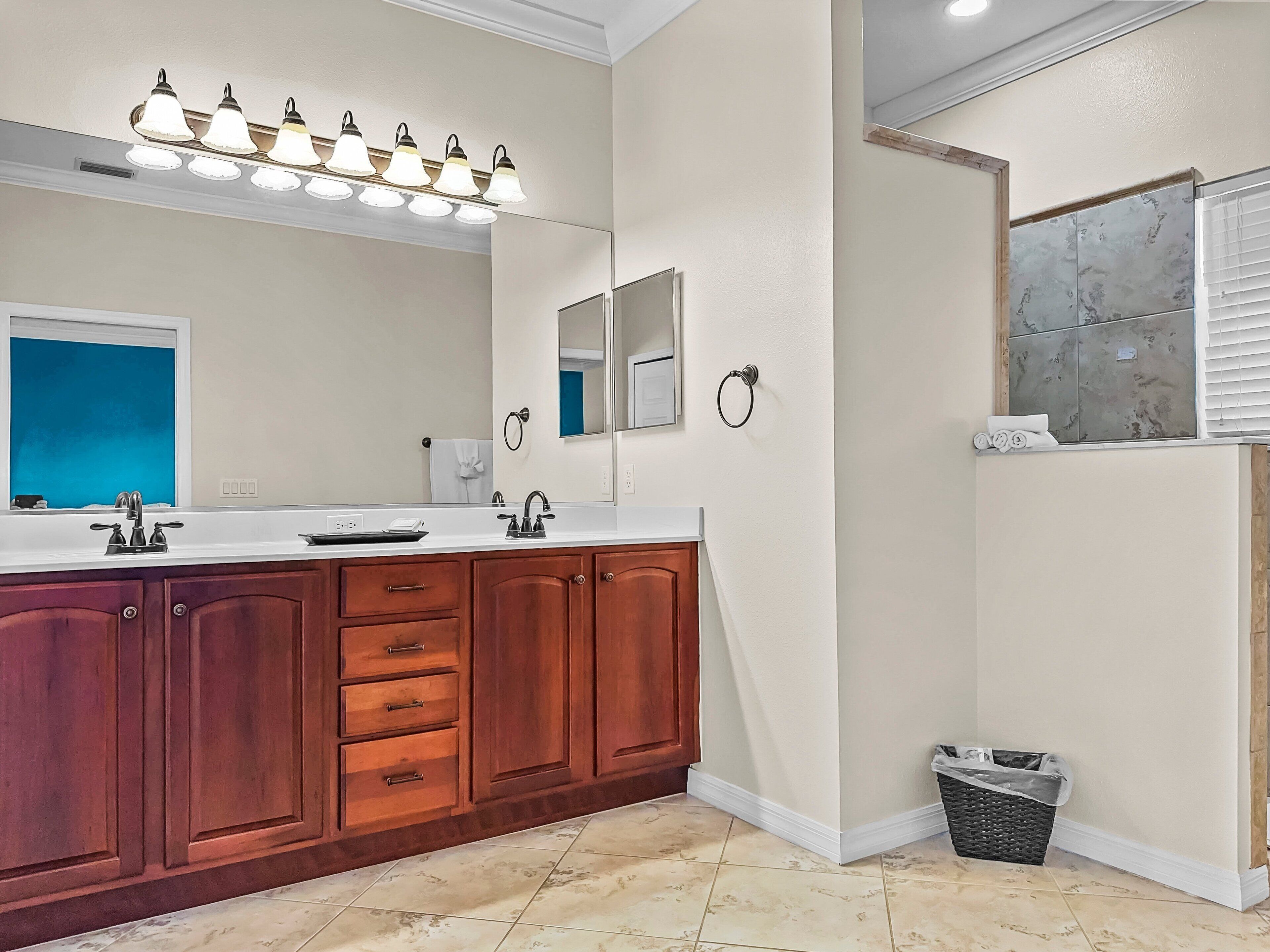 A bathroom with a large vanity, a mirror, a towel ring, and a trash bin.
