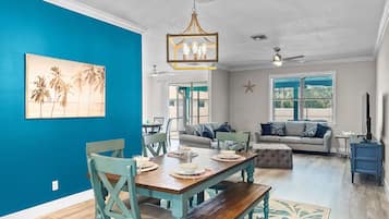 Un comedor con una mesa y sillas de madera, un ventilador de techo y una decoración de estrella de mar en la pared.