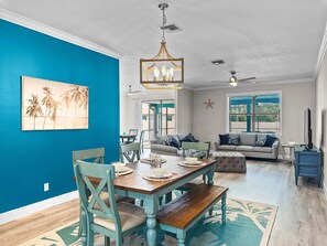 A dining area with a wooden table and chairs, a ceiling fan, and a starfish decoration on the wall. - Coastal Oasis 3 (Nokomis)