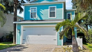 A two-story house with a white garage door, surrounded by palm trees and a well-maintained lawn. - Coastal Oasis 3 (Nokomis)