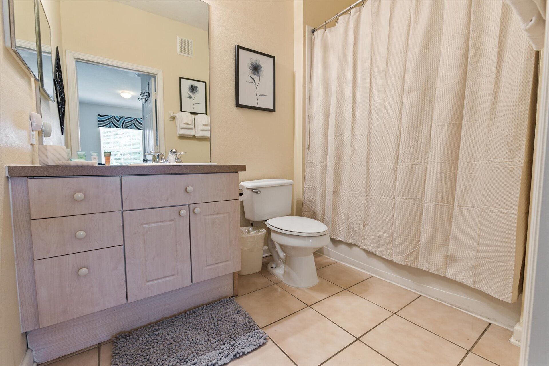 A bathroom with a vanity, toilet, and shower curtain.