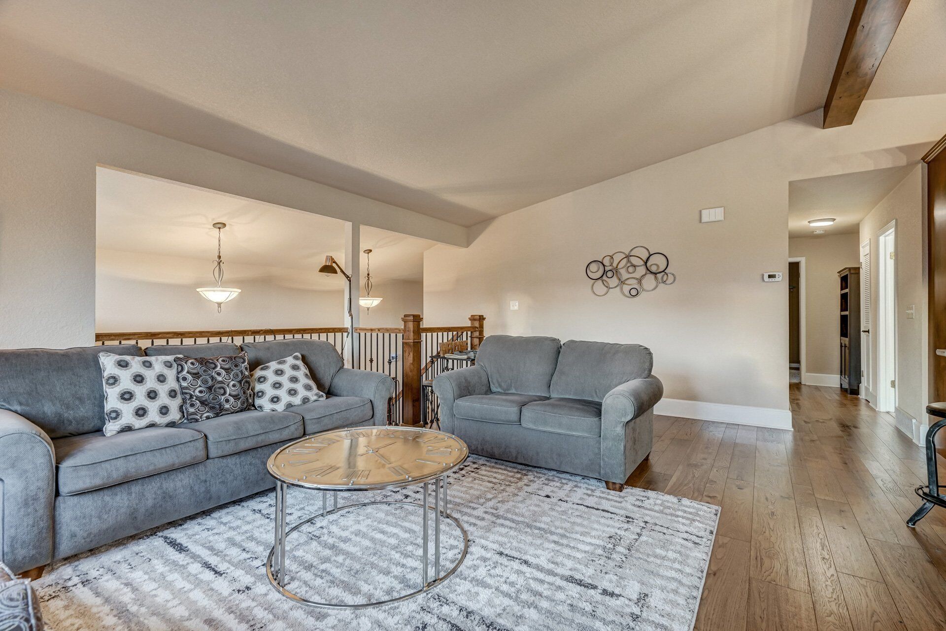 A spacious living room with a grey sofa, a round coffee table, and a patterned rug.