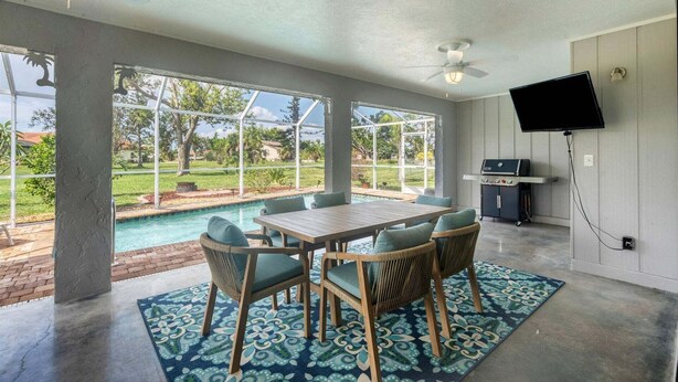 Une pièce spacieuse avec une piscine, un espace salon extérieur, une télévision et un barbecue.