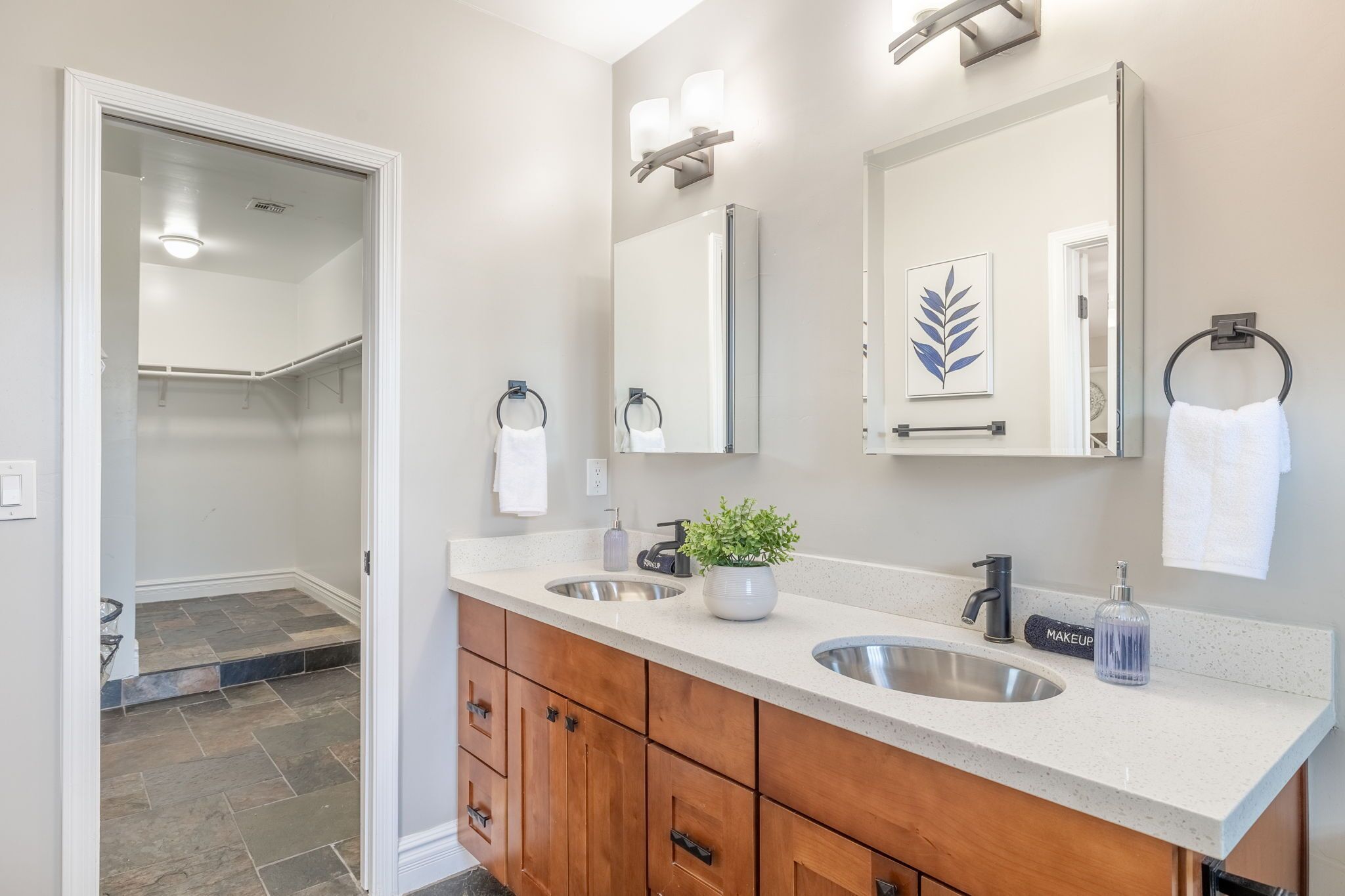 Une salle de bain moderne avec un meuble-lavabo à deux vasques, un grand miroir et une plante en pot.