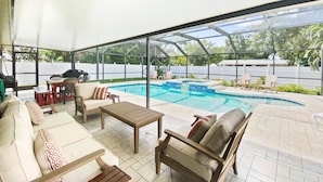Ein überdachter Außenbereich mit Pool, Sitzgelegenheiten und Blick ins Freie.