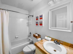 Ein Badezimmer mit Badewanne, Toilette, Waschbecken und einer Duschvorhang.