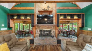 A spacious living area with a fireplace, wooden beams, green walls, and comfortable seating. - Cool Goose Landing Private Dock Large Deck Game Room 61 (Cadiz)