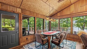 A wooden interior with a dining table, chairs, and large windows offering a view of the outdoors. - Cool Goose Landing Private Dock Large Deck Game Room 61 (Cadiz)