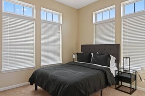 A bedroom with a large bed, two bedside tables, and three windows with blinds. - Cozy 3bd, 3BA Downtown Indy (Indianapolis)