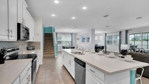 A modern kitchen with white cabinetry, a central island, and a dining area with a view. - Cvt1840 (Kissimmee)
