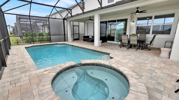 A swimming pool with a hot tub, surrounded by a patio area with outdoor furniture and a covered seating area. - Cvt1840 (Kissimmee)