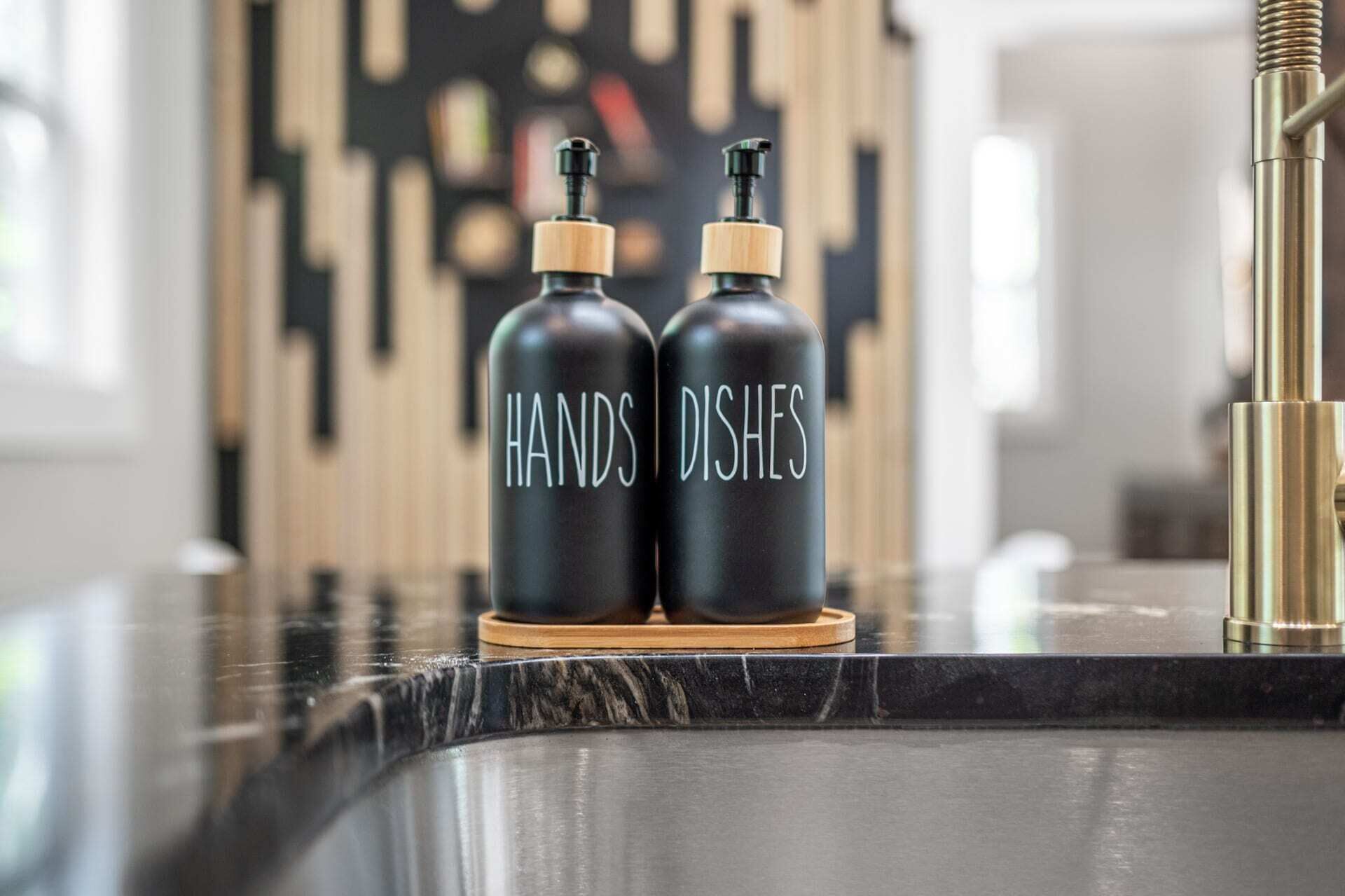 Twee zwarte flessen met houten dopjes, voorzien van de tekst 'HAND DISHES' op een houten onderzetter.