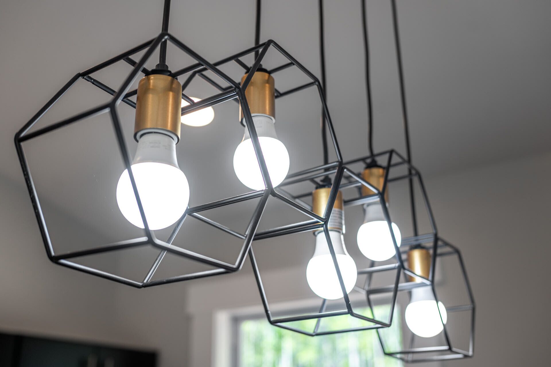 Un luminaire suspendu de forme géométrique, doté de plusieurs ampoules.