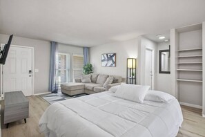 A modern bedroom with a large bed, a sofa, a desk, and a wardrobe. - Cozy 3BR Home Family-friendly Near Attractions (San Antonio)