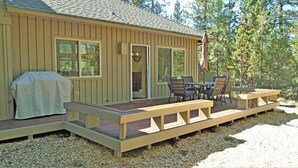 Une terrasse en bois avec une table et des chaises, un barbecue et un espace salon abrité.