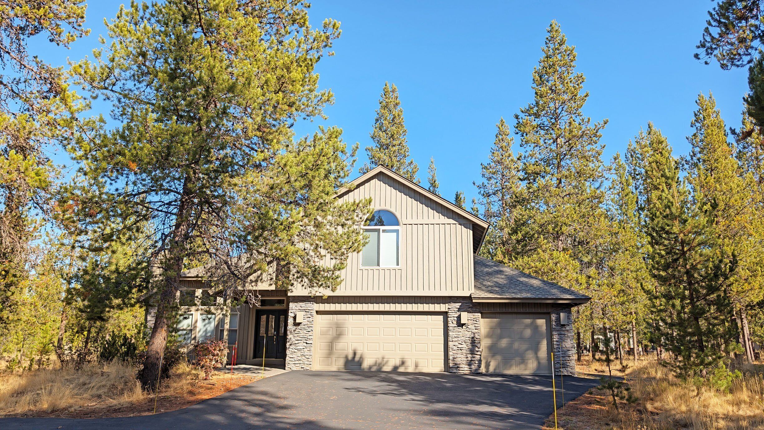 A single-story house with a stone foundation, a garage, and a driveway leading to the entrance.