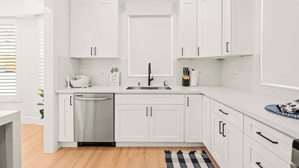 A modern kitchen with white cabinetry, a stainless steel dishwasher, and a black faucet. - Cozy Retreat Near Downtown Perfect for Families (Long Beach)