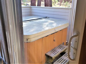 A small, enclosed outdoor hot tub area with a wooden bench and a metal ladder. - Coyote 7 (Bend)