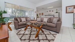 Een moderne woonkamer met een hoekbank, een glazen salontafel en een kamerbreed tapijt met een patroon.